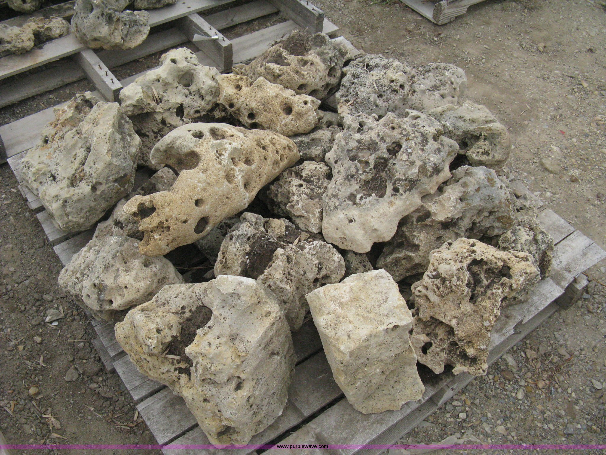 Various sizes of weathered holey limestone boulders on pallets in