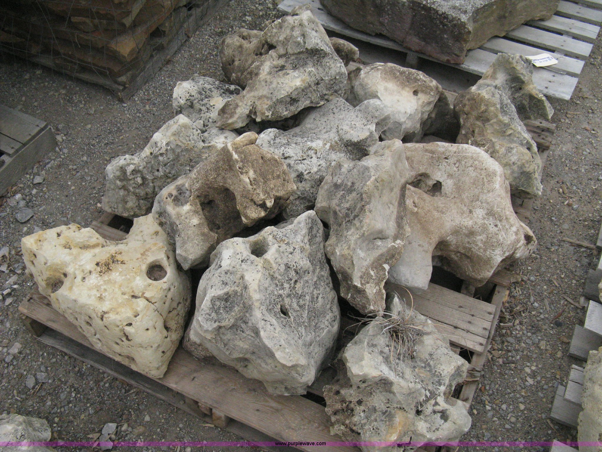 Various sizes of weathered holey limestone boulders on pallets in ...